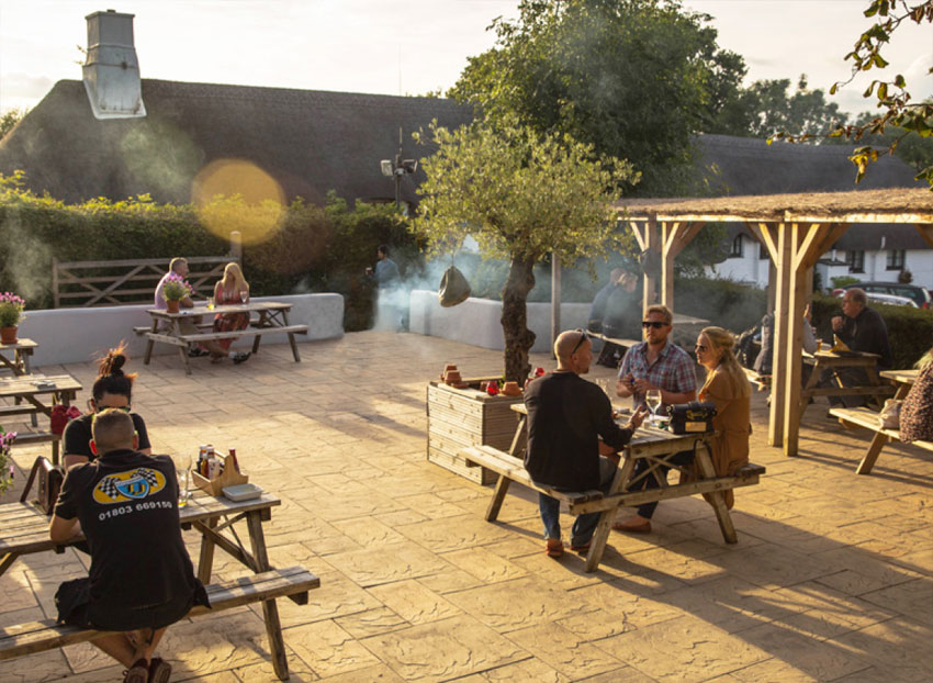 People sitting down at tables outside the pub People sitting down at tables outside the pub